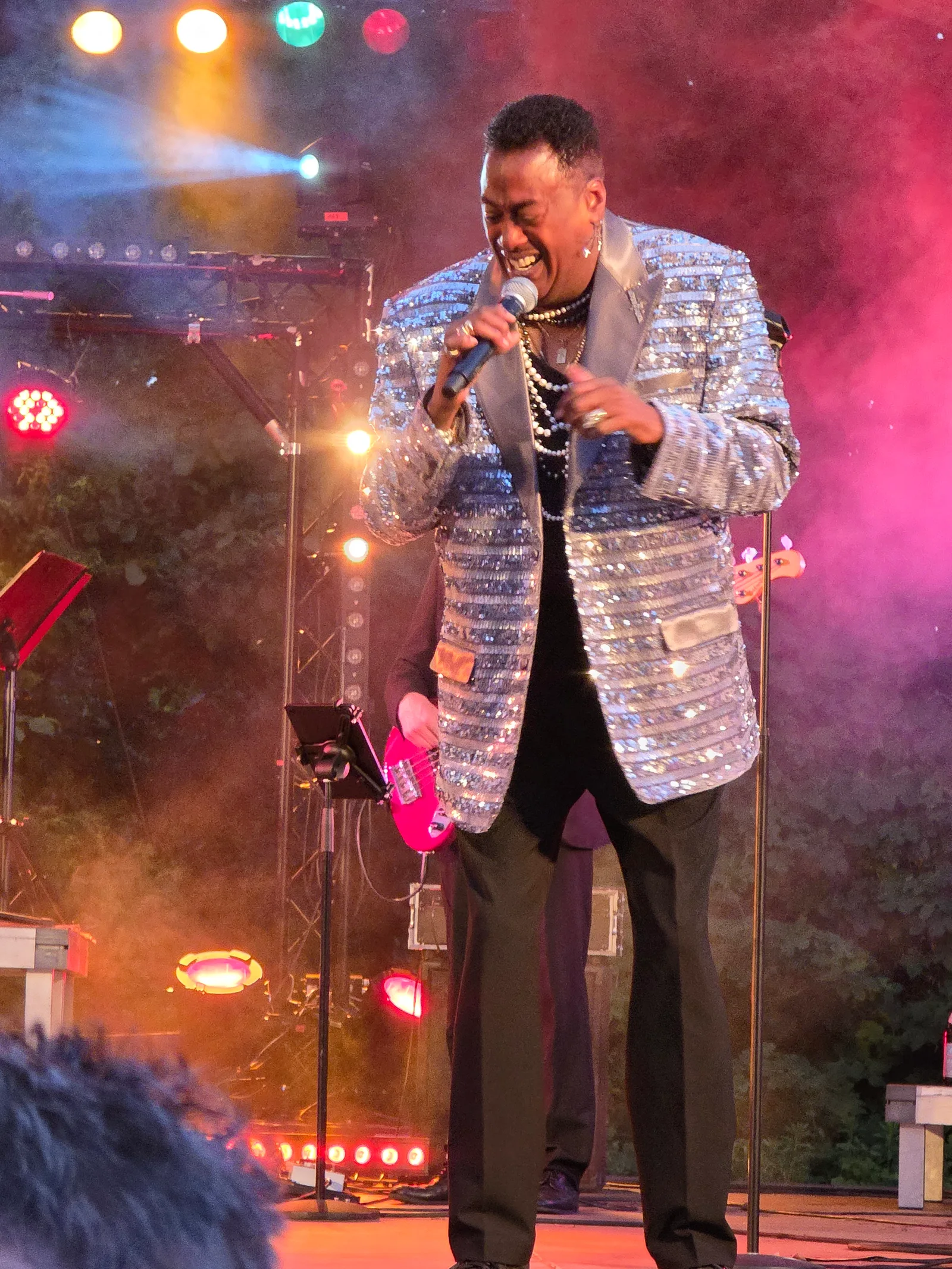 Keith singing in a silver jacket under colourful stage lights