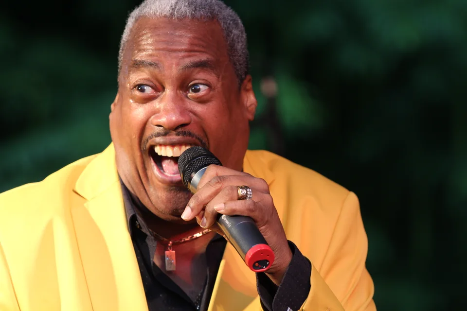 Keith joyfully singing in a yellow jacket