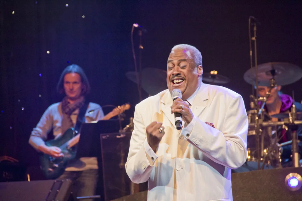 Keith singing in a white suit, accompanied by his band